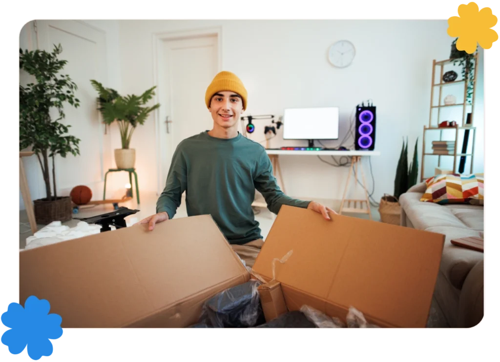 A smiling young man is unpacking a box in his apartment