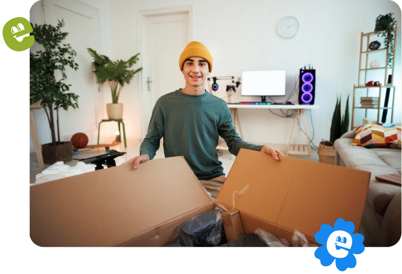 A smiling young man is unpacking a box in his apartment.
