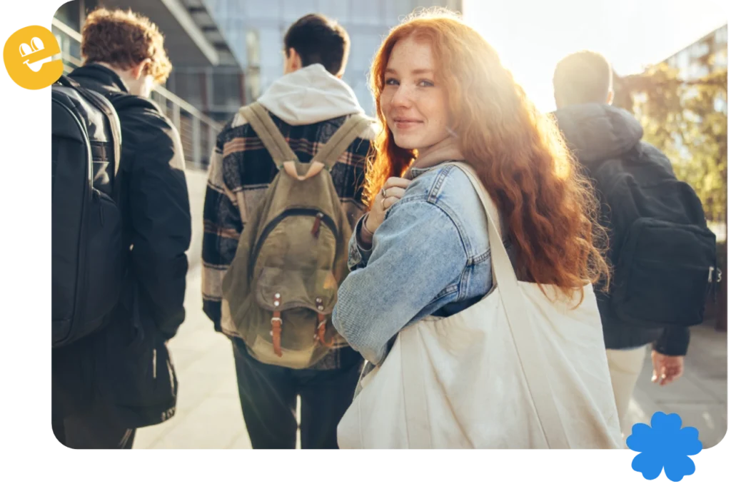 A group of young people is walking away from the camera. A young woman turns towards the camera with a smile.