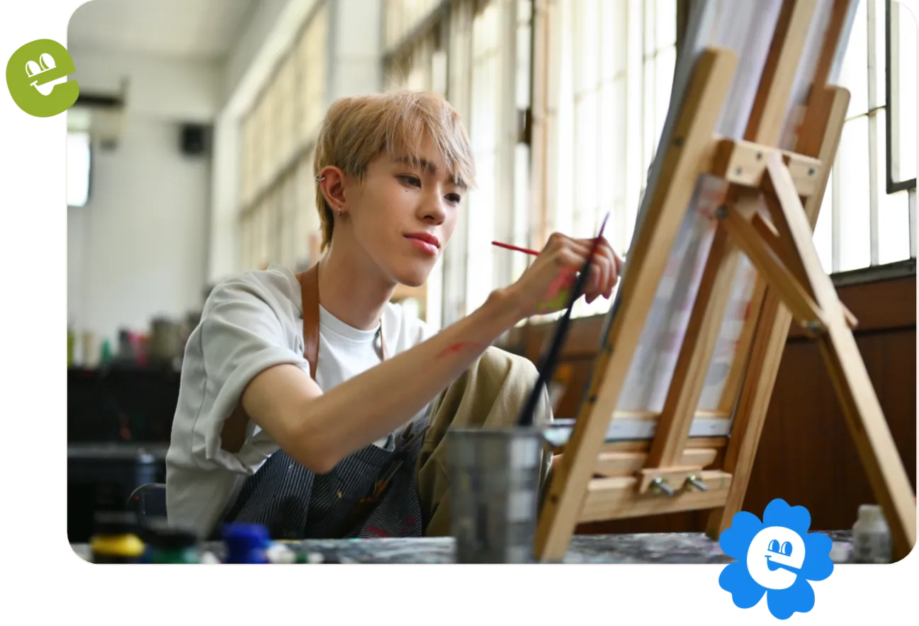 An LGBTQ artist with colored hair doing artwork in a workshop studio.